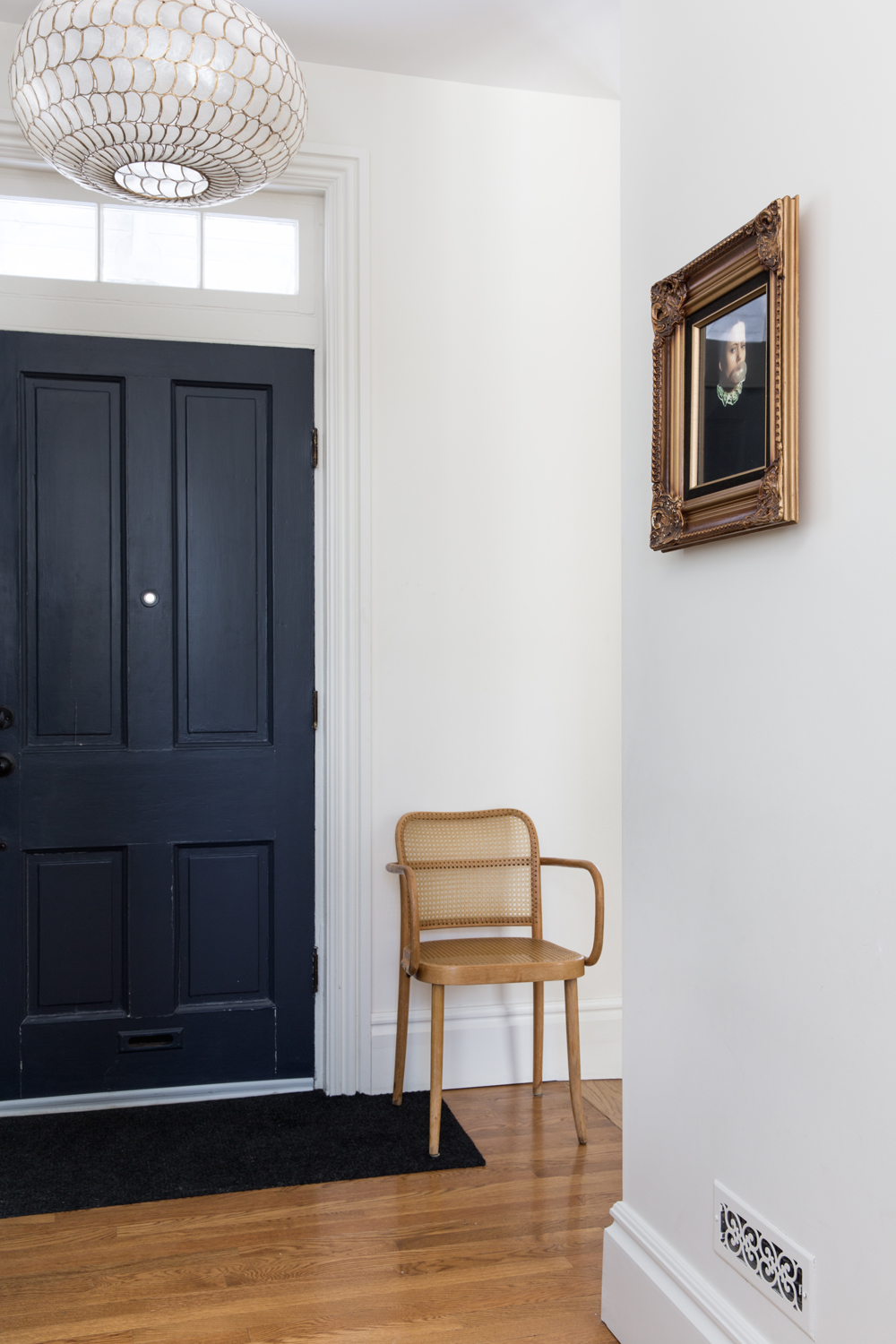 Go Minimalistic Entranceway to Parisian-inspired home with Thonet chair and gold-framed painting