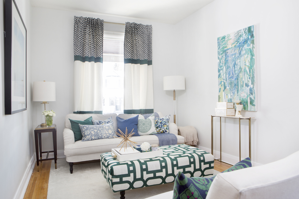 Form a Pattern white living room with white and green patterned drapes, ottoman and green and blue abstract