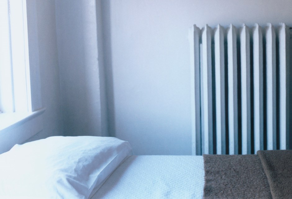 3. Lower the Temperature in Empty Rooms Bedroom with a bed and radiator heating