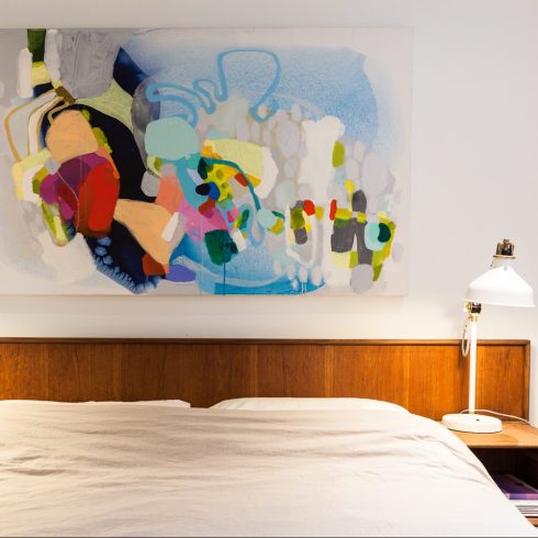 Splashes of Colour A brightly coloured piece of artwork hanging over a bed