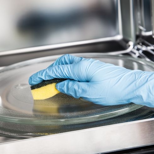 Use Vinegar or Lemon Juice and Water to Clean Tough Spots scrubbing microwave with sponge