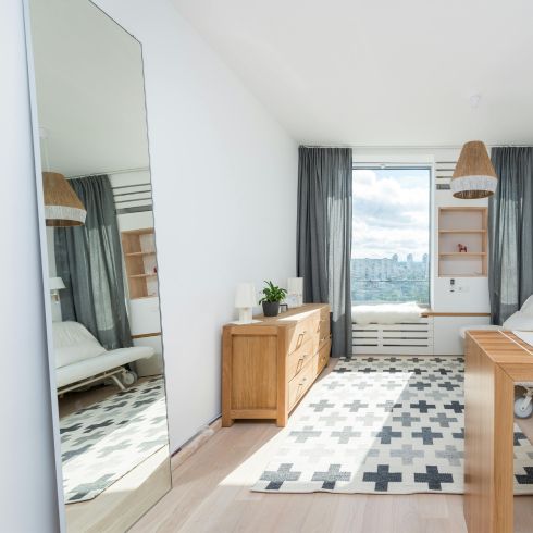 Make Use of Mirrors A bright light bedroom with a large full-length mirror leaning against a wall.