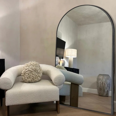 Mirror, Mirror on the Wall Arched full-length metal framed floor mirror beside a sofa chair.