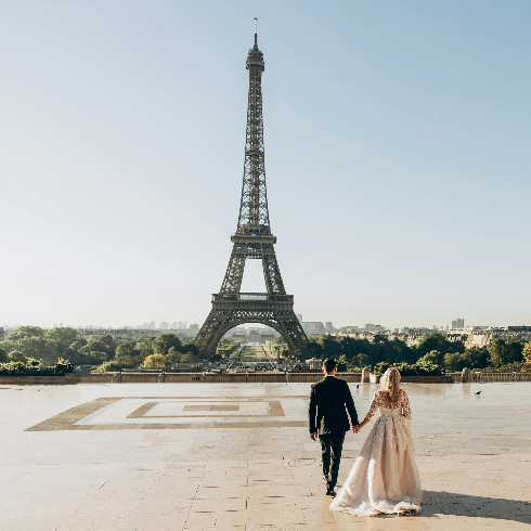 Paris, France A bride and groom walking toward the Eiffel Tower in Paris, France.