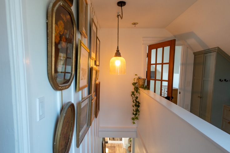 Artful Touches The top landing of a stairway with a wall displaying vintage art on the left hand side