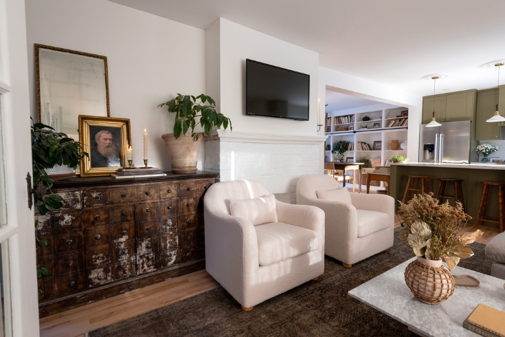 Open It Up A living room wall with an apothecary cabinet, fireplace, TV and two large white armchairs