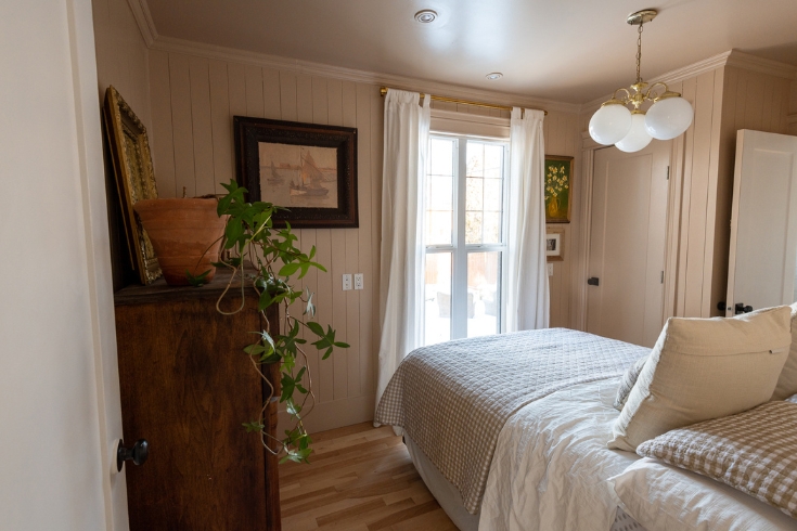 Pink Perfection A bedroom with soft pink walls, a bed, a large dresser and a window