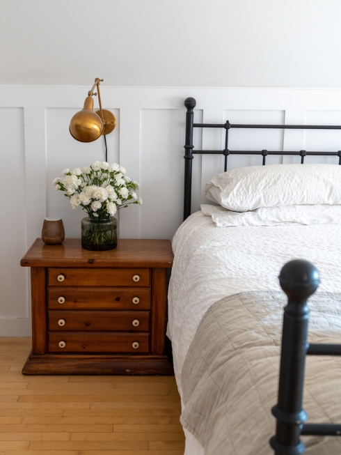 Simply White … For Now A black iron headboard, bed and side table against a white wall with panelling