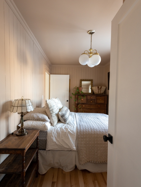 A Fantastic Find A bedroom with soft pink walls, a bed, side table, and large dresser on the far wall