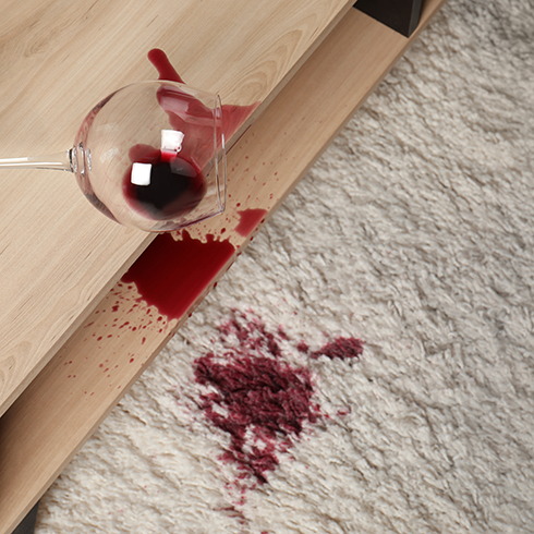 Red wine stains Overturned glass and spilled red wine on white carpet indoors, above view