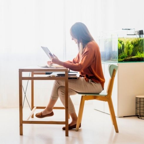 Add a Water Feature Female freelancer working at home sitting at desk using tablet with aquarium