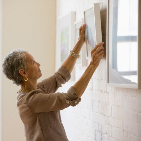 Have Some Pictures of Those Who Support You Mixed race woman hanging pictures on wall