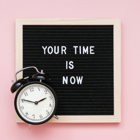 Put Inspiring Images or Messages on the Walls Your time is now. Motivational quote on letter board and black alarm clock on pink background. Top view Flat lay Concept inspirational quote of the day.