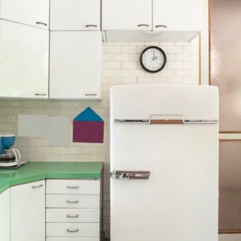 Outdated Appliances old, outdated kitchen with worn white cabinets and fridge