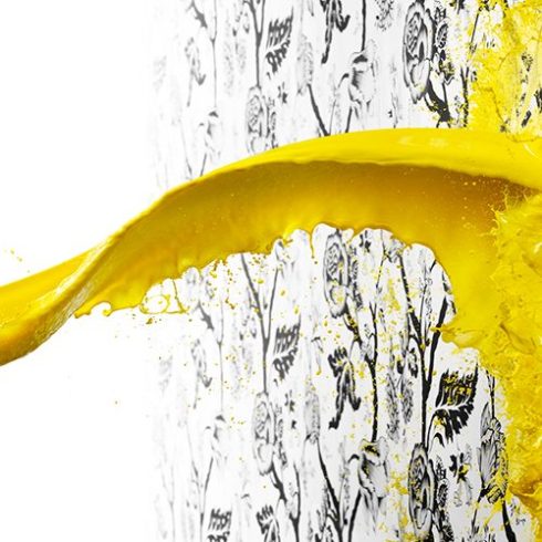 Paint it Light Yellow paint being splashed on a white wall