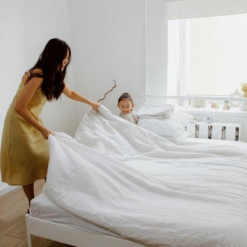 Everyday Cleaning Routines Mom and daughter making the bed in a white room