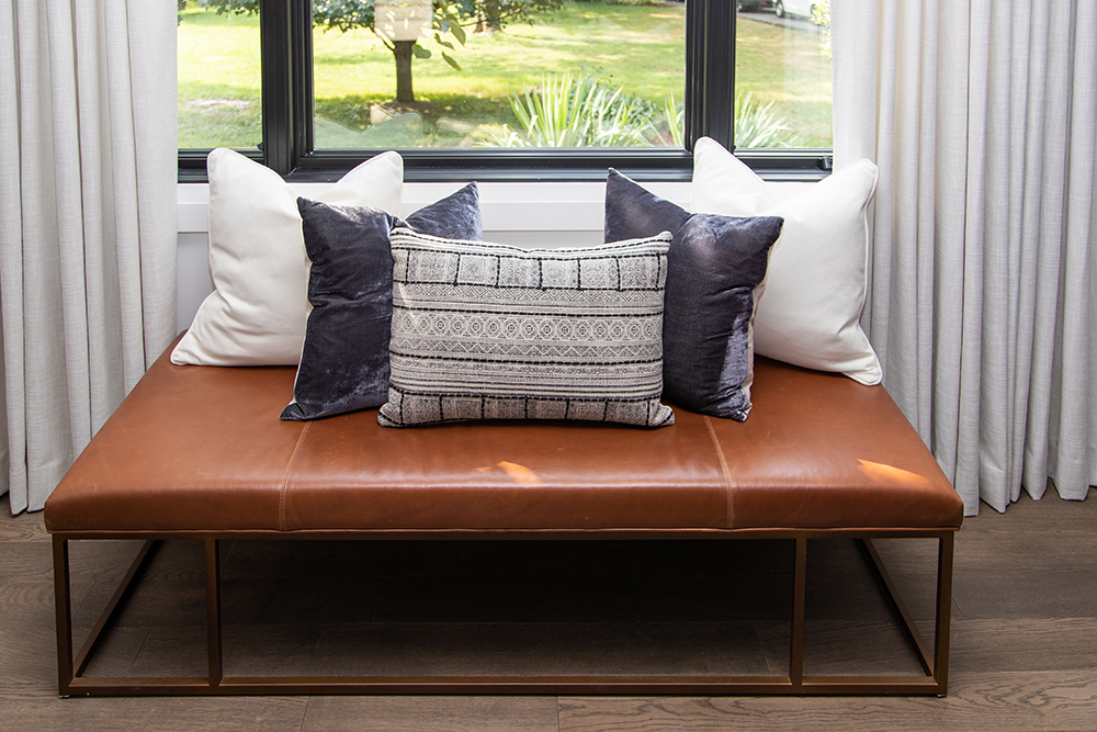 Window Seat leather chair with pillows in front of window