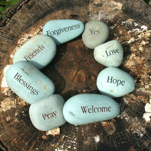 Wise Words Eight river stones engraved with motivational words sit on a tree stump as part of a memorial garden