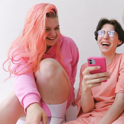 You Constantly Check Your Phone Two friends laughing and looking at a phone