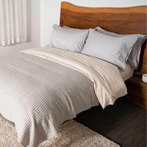 Skylark+Owl Grey bedsheets in a wooden bed.