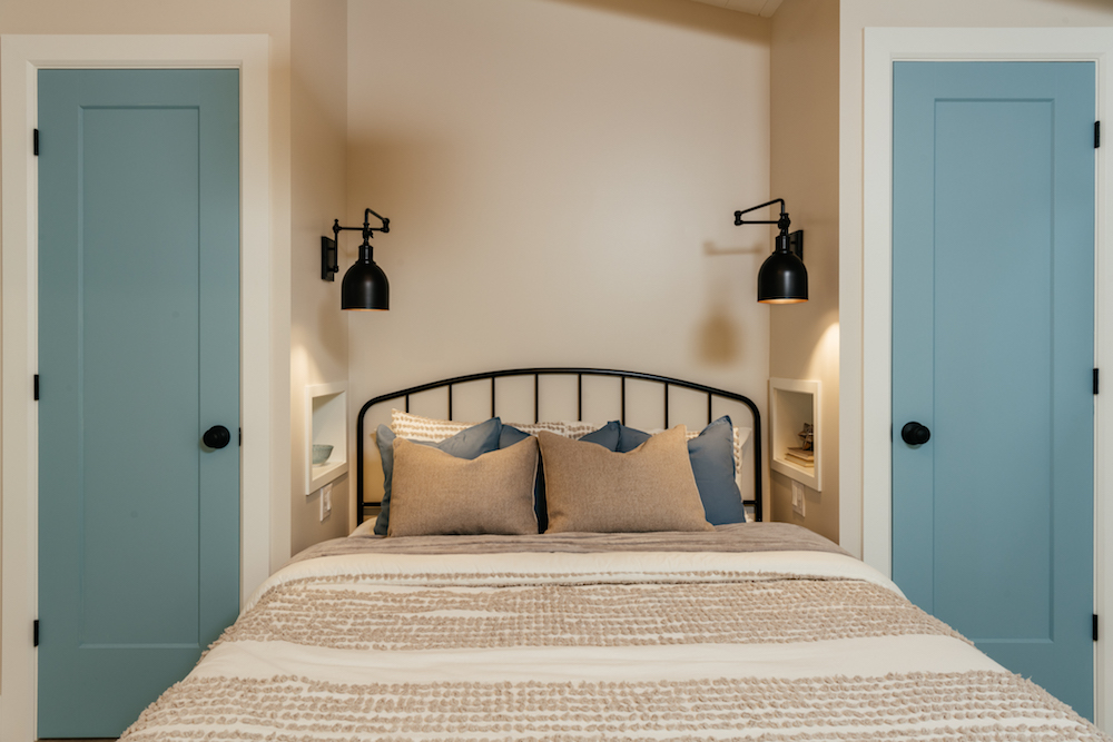 Lighten Up — With Less Space cozy beige bedroom with black sconces framing bed