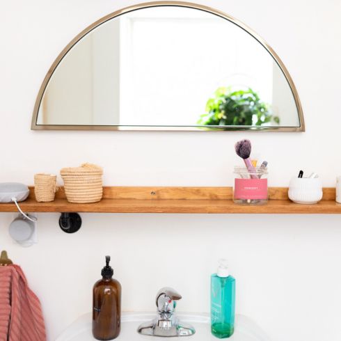 Shelf It Small bathroom with wood shelf above sink and gold half crescent mirror