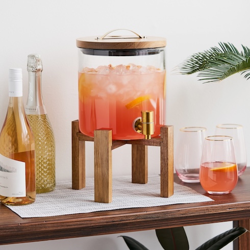 Simplify Your Sips A wood-and-glass drink dispenser is filled with a festive orange beverage on a table.