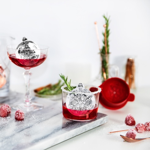 Remember: You Can Never Have Enough Ice Two glasses are filled with a red drink and ornament-shaped ice cubes on a festive table.