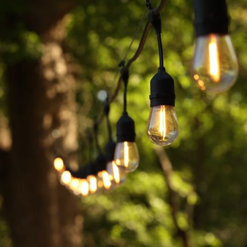 Mistake #7: Not Adding Lights to Your Space string lights tied to a tree close-up in summer.
