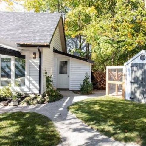 Mistake #5 Not Planning What to Plant in Advance Small backyard with grass and paved path, modern white shed and minimalist landscaping.