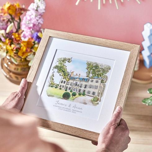Commission a Custom Illustration A person holding a custom illustration of a wedding venue in a frame