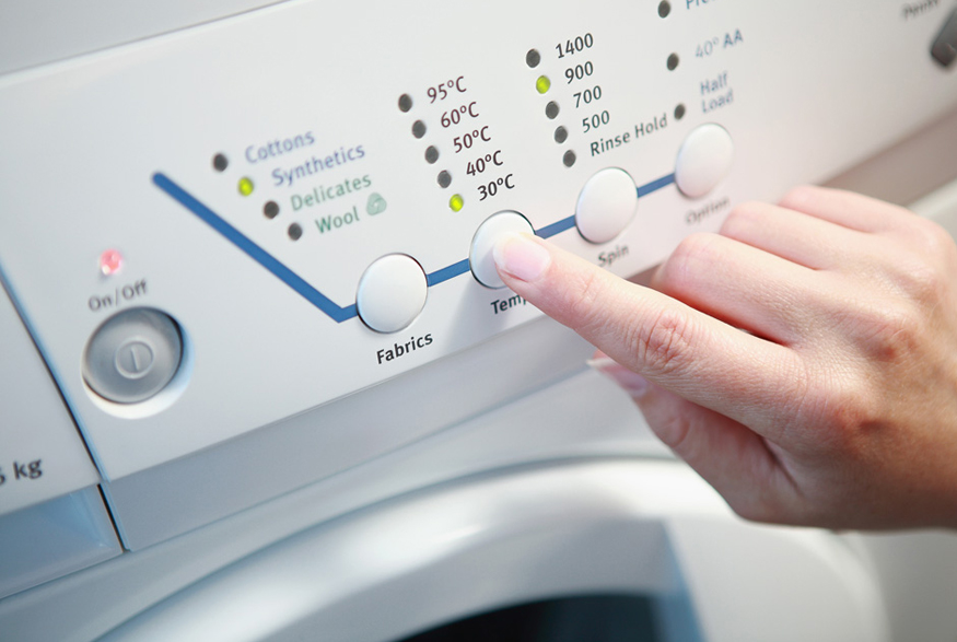 14. Wash Laundry in Cold Water Woman turning washing machine to cold water
