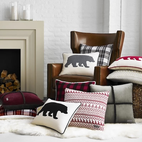 Incorporate Functional Festive Decor An array of cozy patterned pillows sit on a brown leather chair in front of a fireplace.