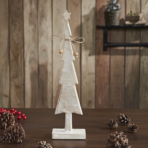 Make Minimalist Merry A small rustic wood Christmas tree figurine sits on a wood table that's covered in pine cones.
