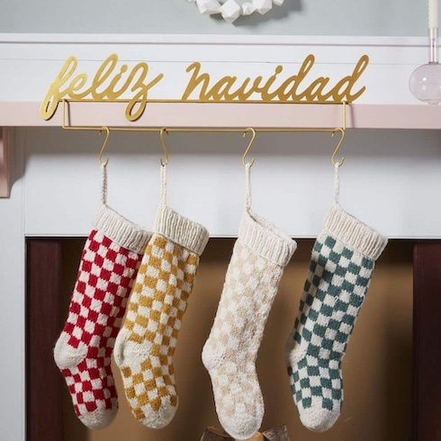 Play With Pattern Four knit stockings in checkered patterns hang from a white fireplace mantle. A sign saying