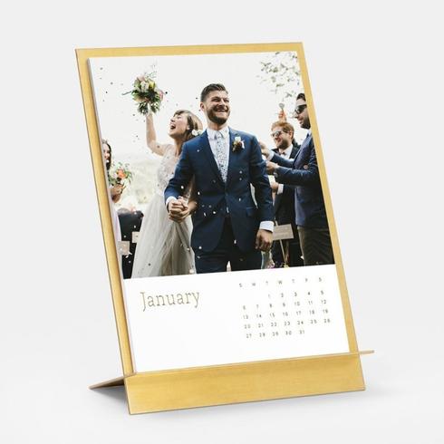 Make a Calendar A brass easel and calendar with a photo of a bride and groom on their wedding day.
