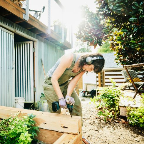 Mistake #2: Not Creating Separate Zones Woman building veggie garden in small backyard