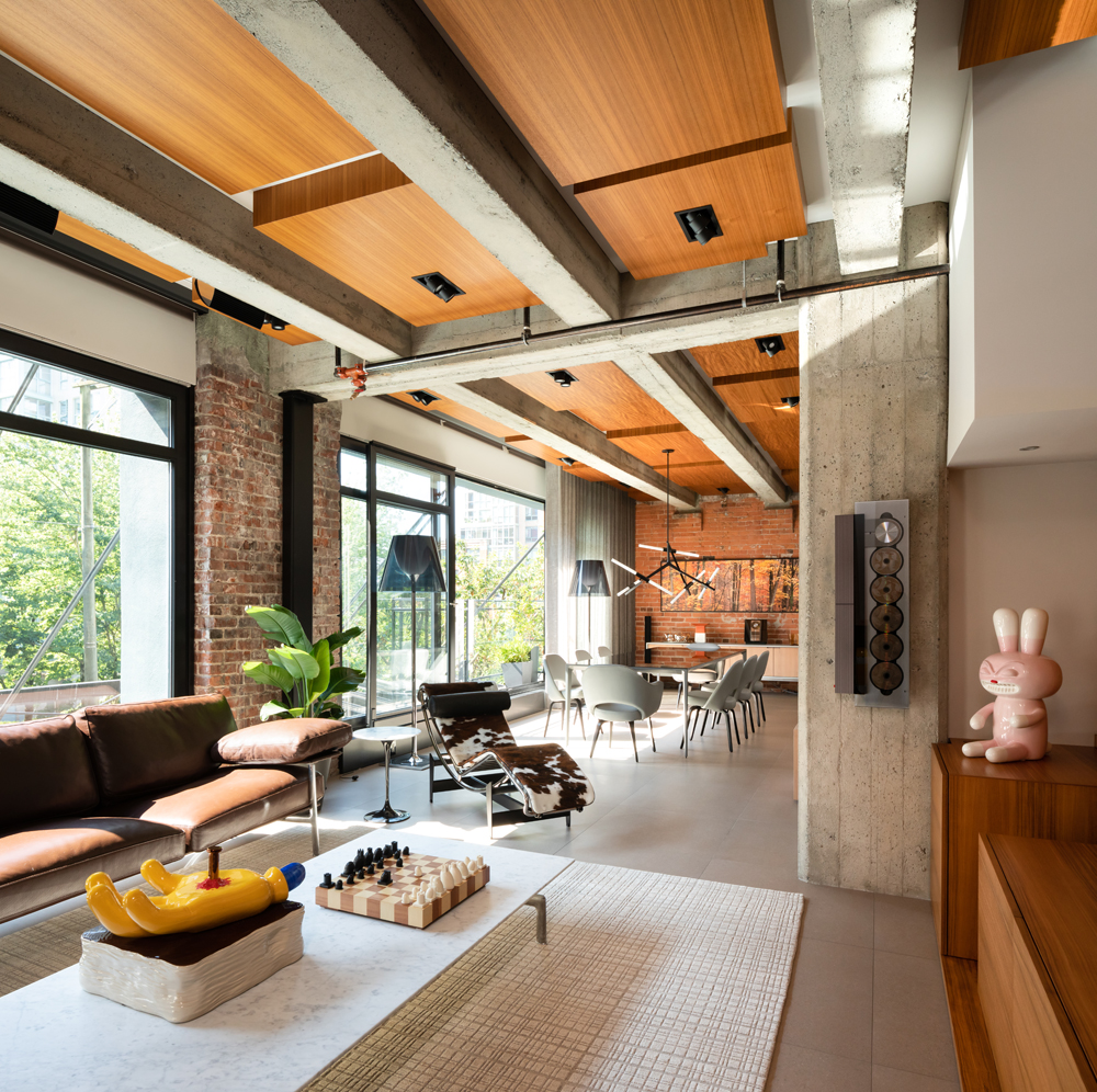 Architectural Digest open loft living dining with concrete ceiling beams, wood ceiling, 5 CD player and bunny sculpture to the right