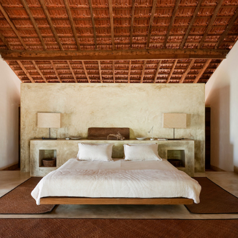 A Symmetrical Aesthetic white bed in white bedroom with exposed beams at ceiling