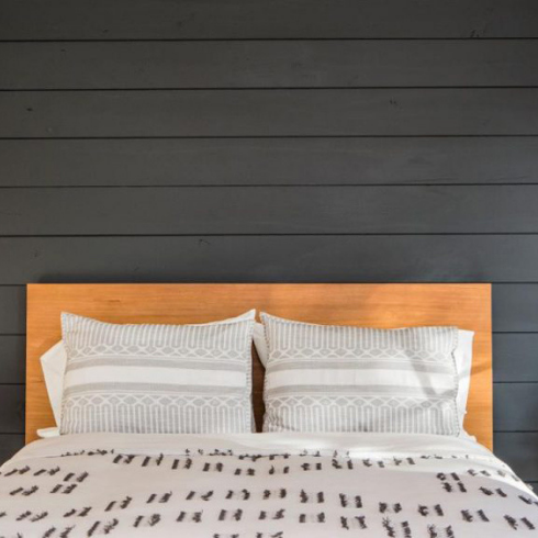 Layout For Less Stress white bed and hanging light bulbs in bedroom with charcoal shiplap wall