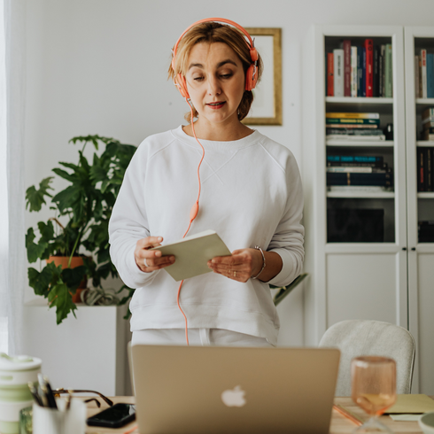 Homes Made For Hybrid Working woman standing on desk at home holding a tablet