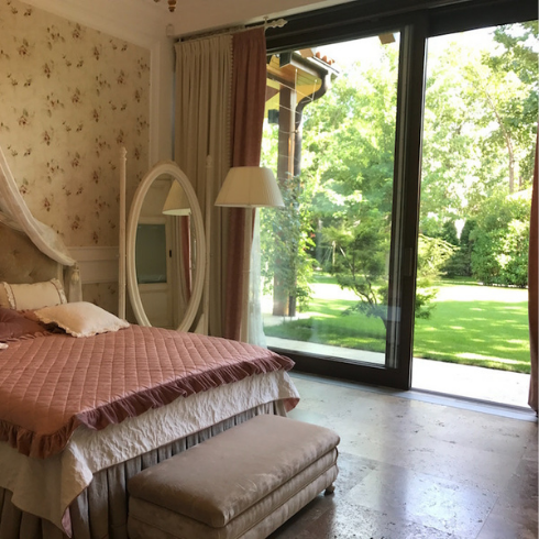 Space Out pink bed in wallpapered bedroom with sliding door to green yard