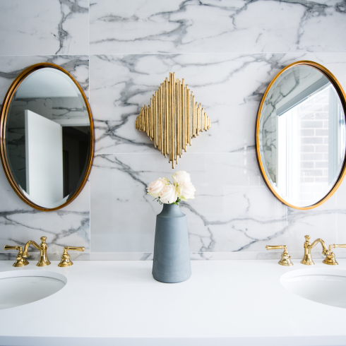 Spa Bathrooms Modern bathroom double vanity with marble-look walls and oval mirrors.